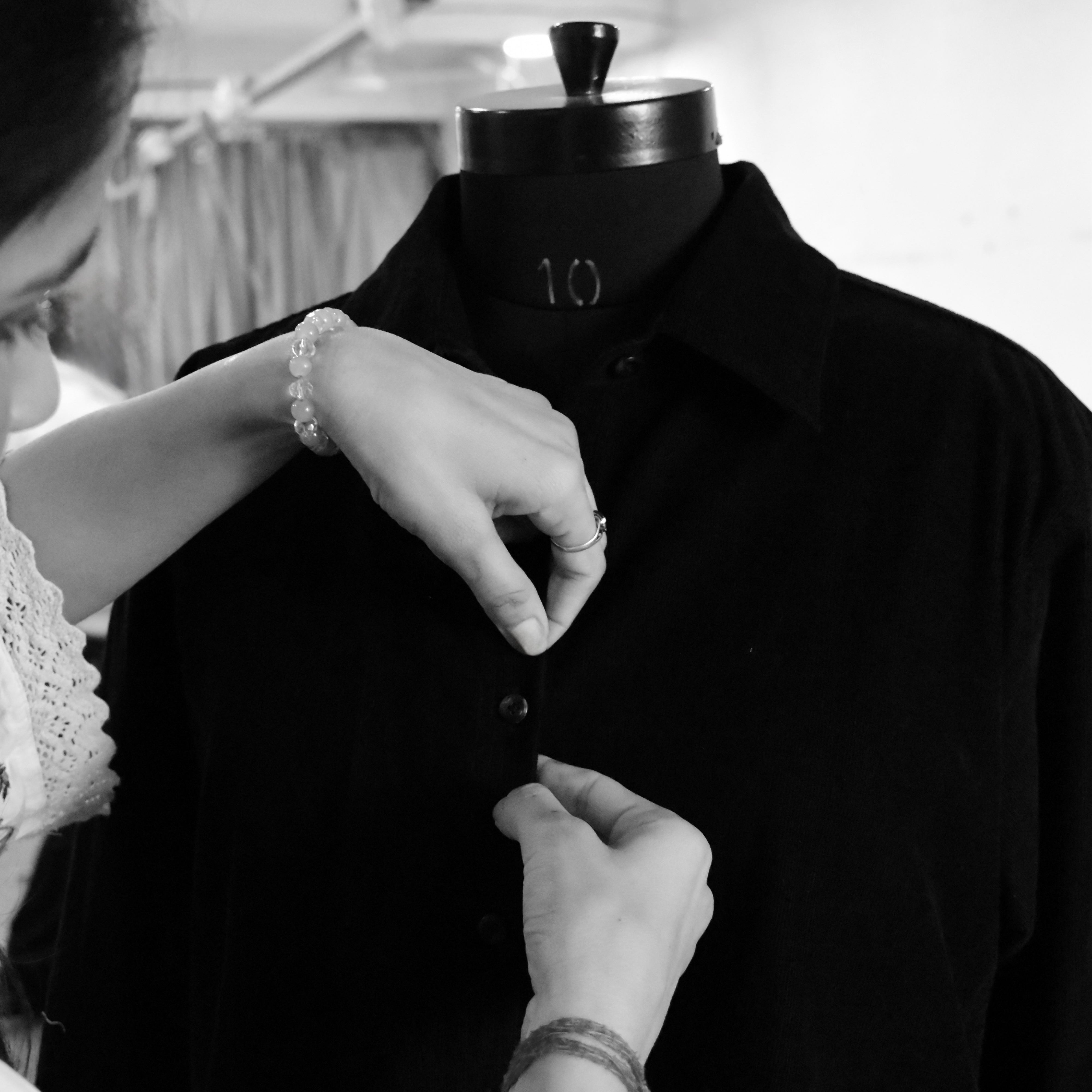 Person adjusting a black shirt on a mannequin in Cloth & Co.'s stitching unit.