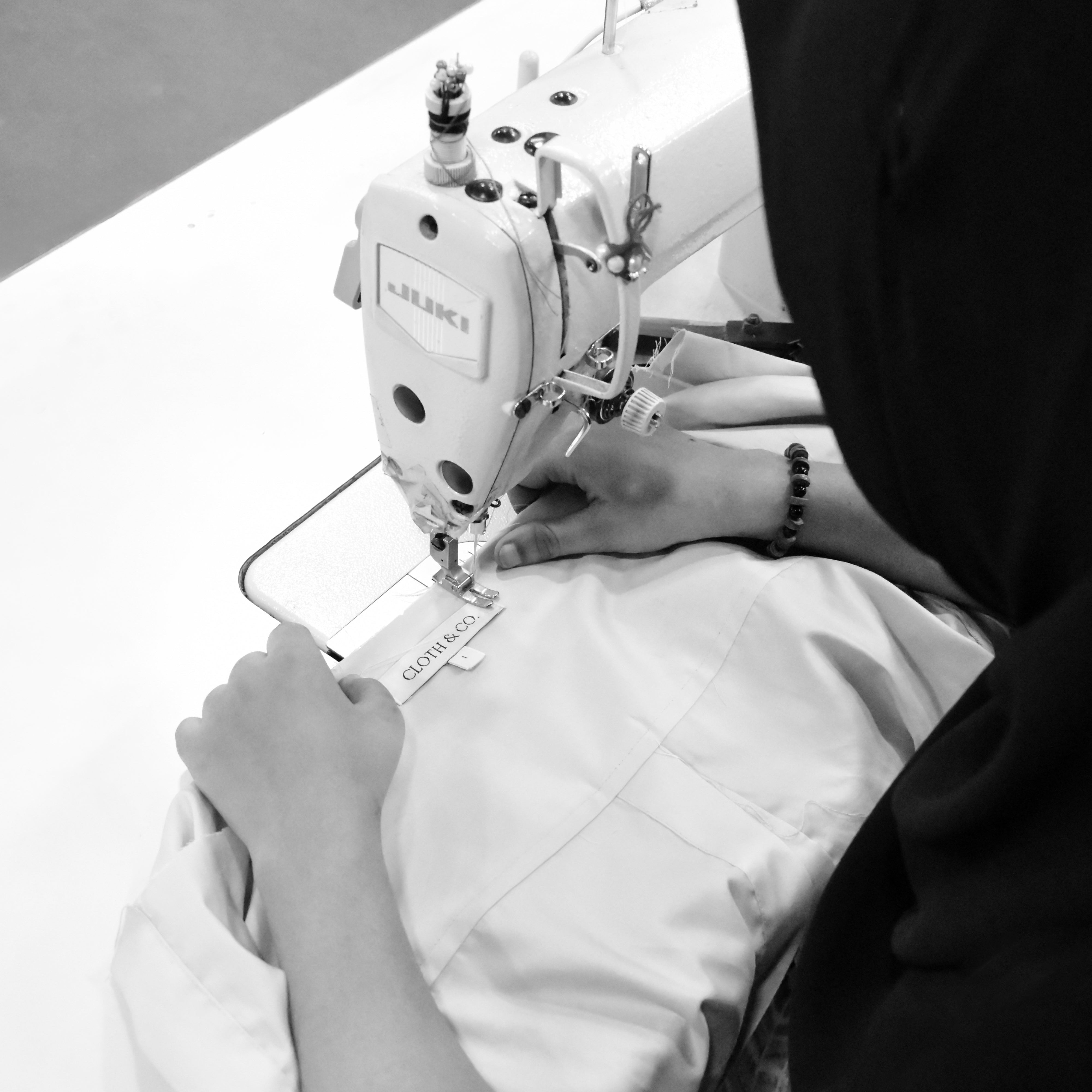 Person using a sewing machine on a table with a blurred background