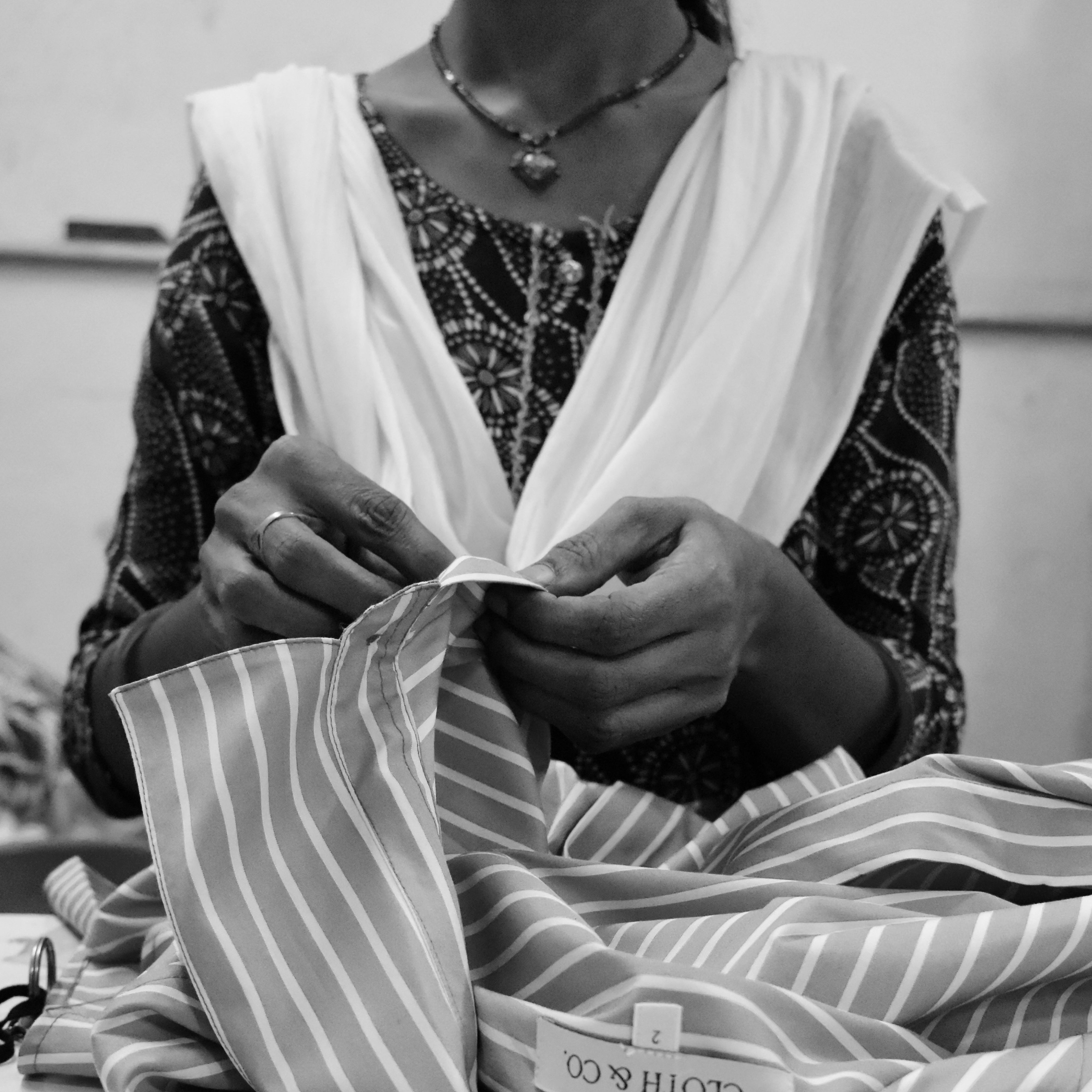 Person holding a striped fabric with 'CLOTH & CO' branding on a plain background